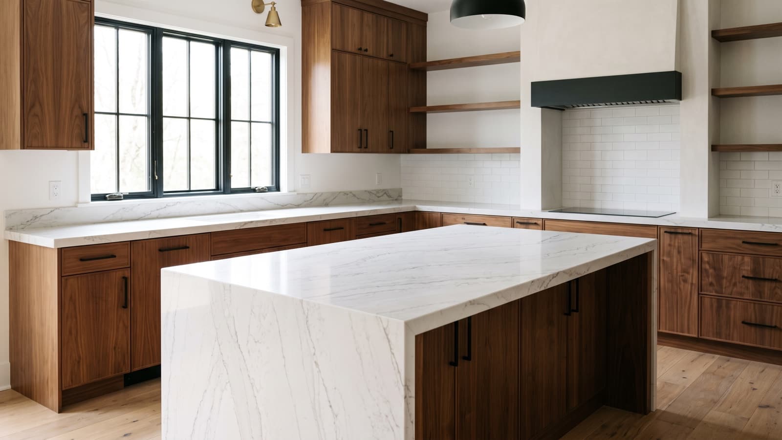White stone kitchen island with a deep edge and waterfall end beside walnut cabinets